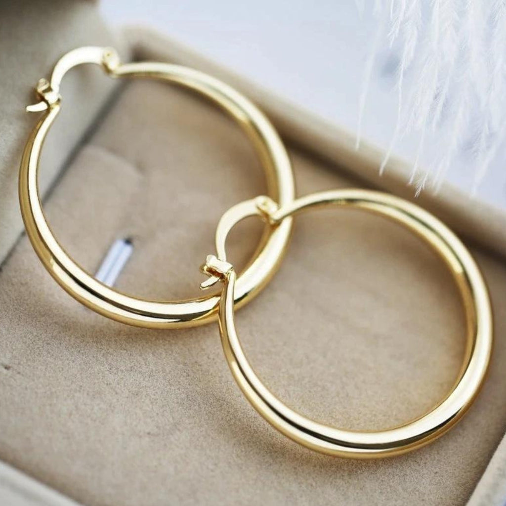 Chunky gold hoop earrings, wide and rounded, in polished gold