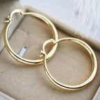 Chunky gold hoop earrings, wide and rounded, in polished gold