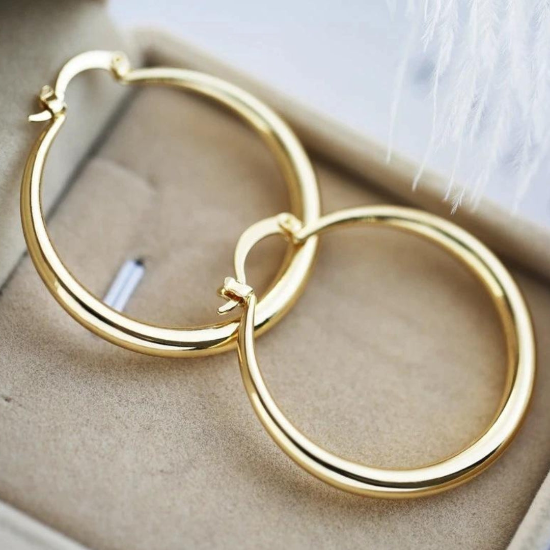 Chunky gold hoop earrings, wide and rounded, in polished gold