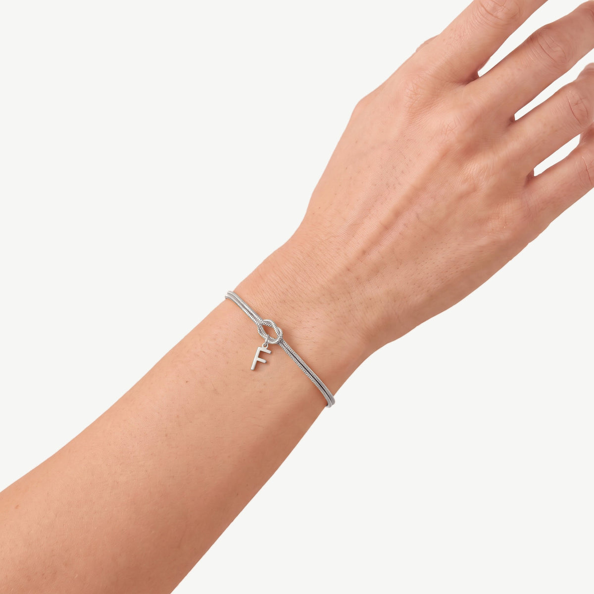 Initial knot bracelet in silver with the letter F on the wrist
