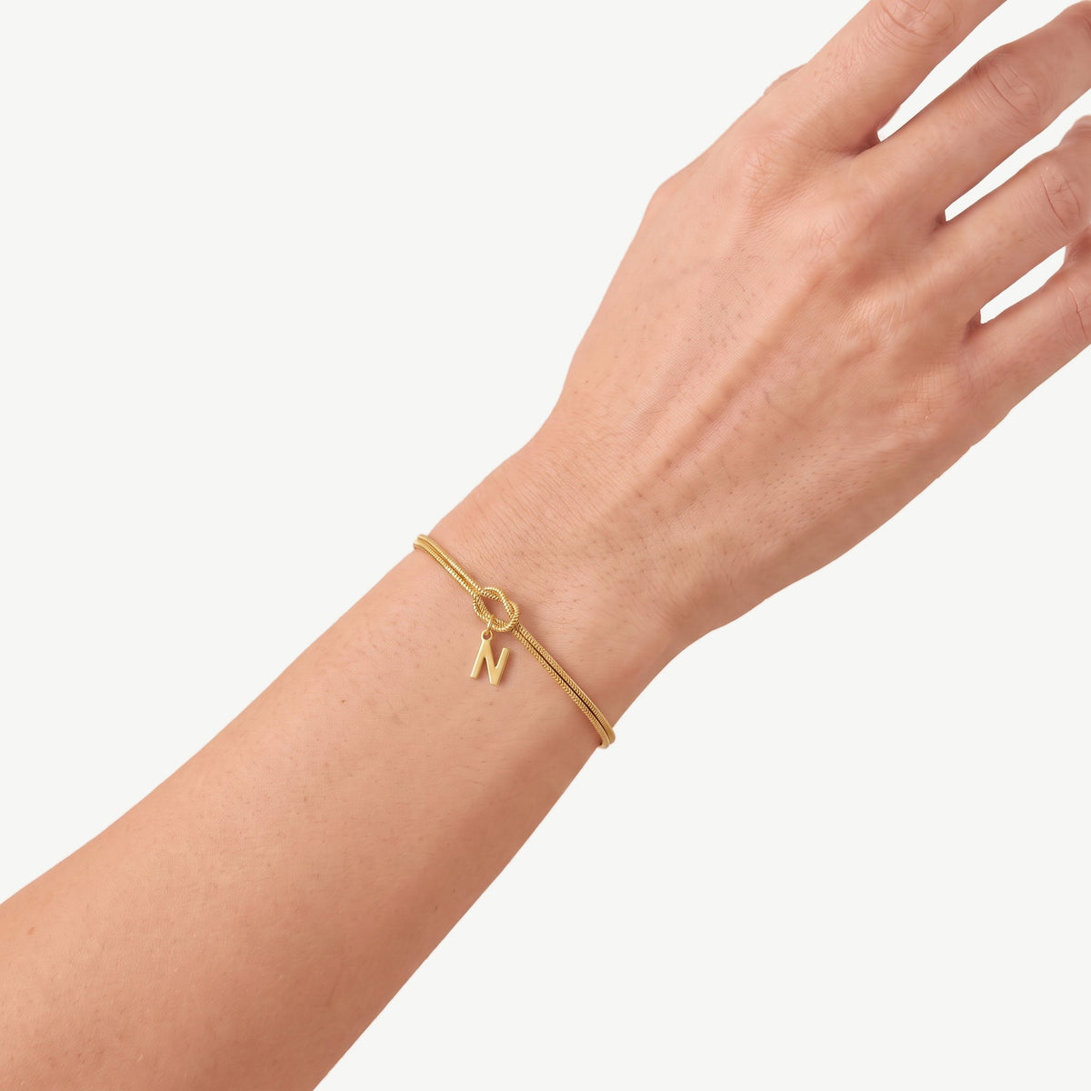 Initial knot bracelet in gold with the letter N on the wrist